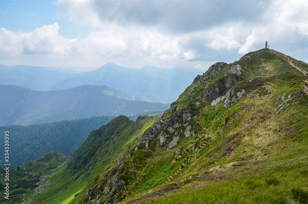 The nice view to the landscape of high mountain Pip Ivan in the cloudy day is opened from the green valley covered with bushes and pathway. Location the Carpathian Mountains, Marmarosy, Ukraine.