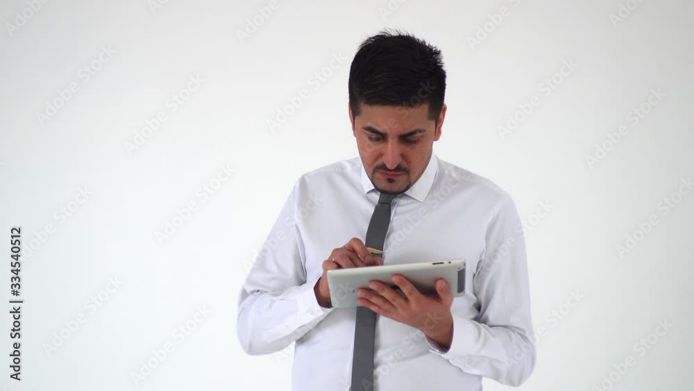 A serious man from the East is working on a digital tablet and scratching his beard A serious man from the East is working on a digital tablet and scratching his beard