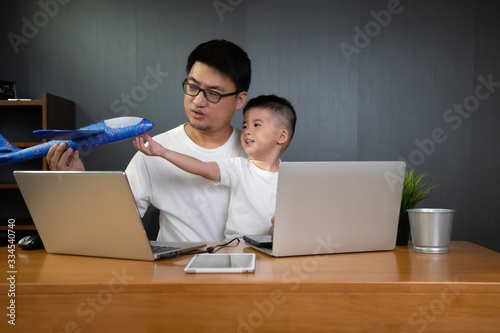Asian man it support working on computer laptop to remote desktop with his son. Work from home concept