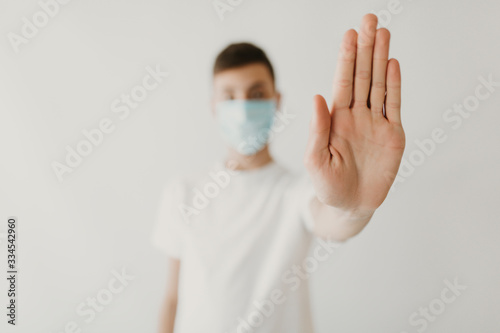 Stop the infection. man in a medical mask against infectious diseases, coronavirus, shows the stop gesture, on white background
