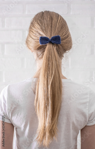 Female hairstyle braid with blue knitted bow tie back view