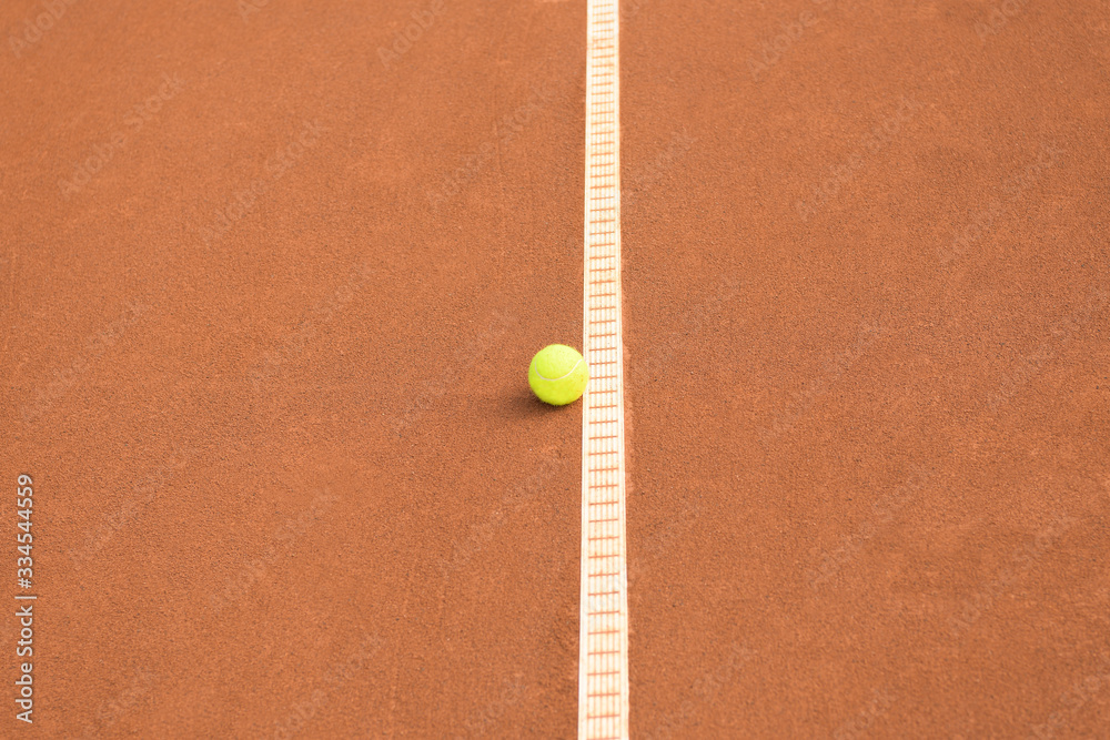 Tennis ball next to a line on a clay tennis court