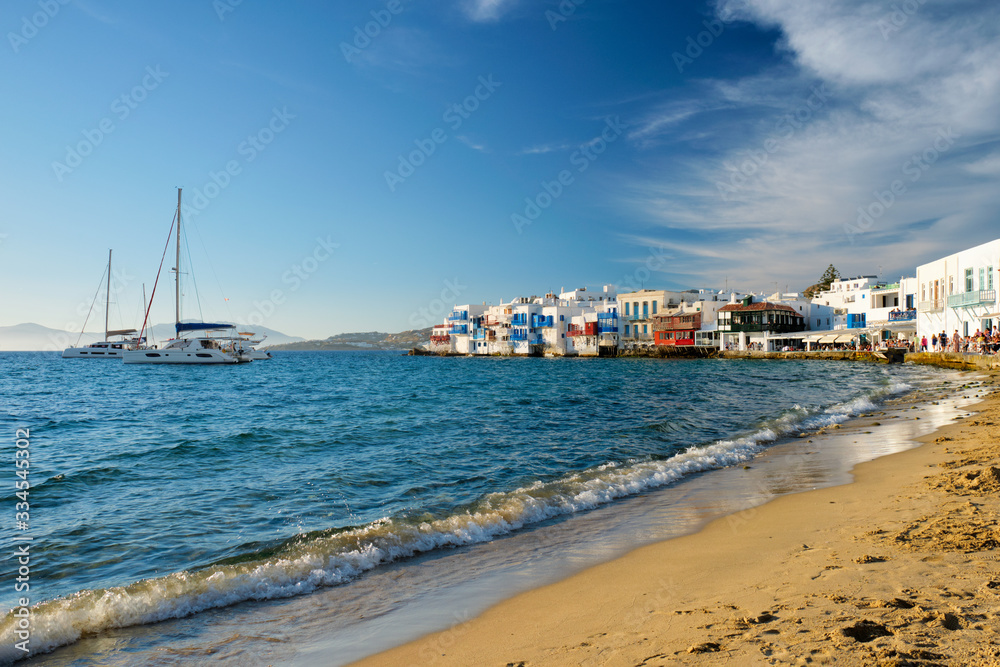 Sunset in Mykonos island, Greece with yachts in the harbor and colorful waterfront houses of Little Venice romantic spot on sunset and cruise ship. Mykonos townd, Greece