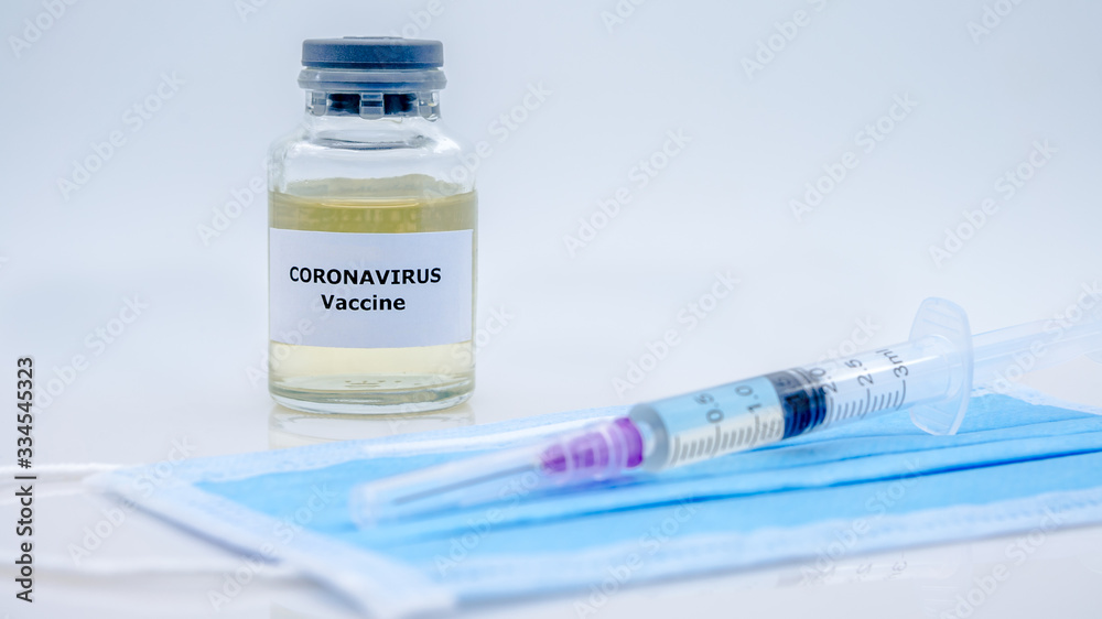 Vaccine and syringe injection for Covid-19 on face mask in scientific laboratory Vaccine and syringe injection for Covid-19 on face mask in scientific laboratory