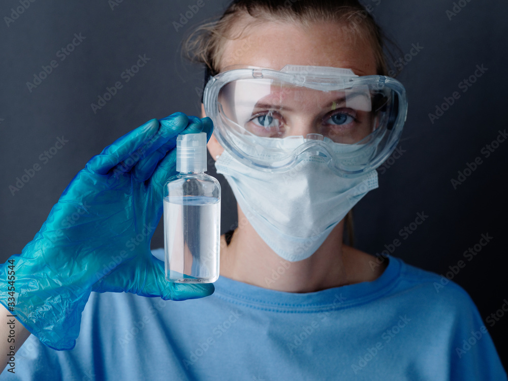 COVID-19 Pandemic Coronavirus. woman in medical mask shows hand sanitizer gel dispenser close up nurse. COVID-19 Pandemic Coronavirus. woman in medical mask shows hand sanitizer gel dispenser close up nurse.