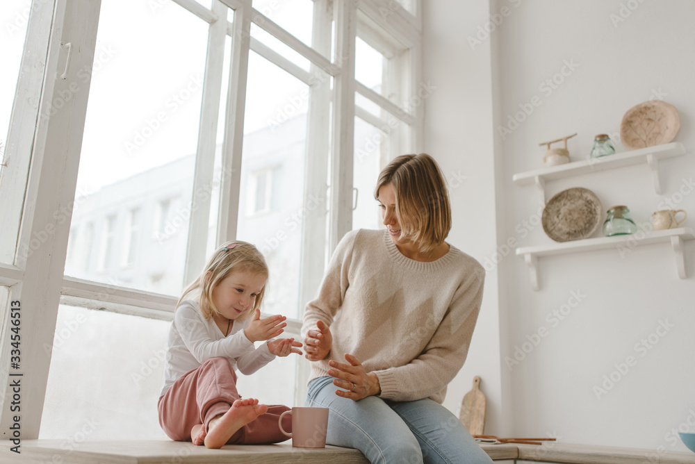 Fototapeta premium A young mother spends time with her little daughter at home.