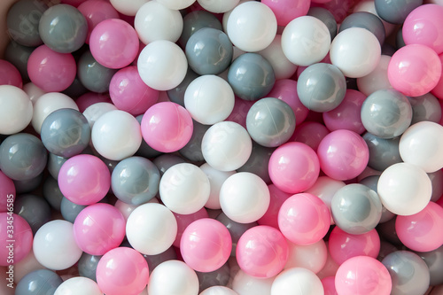 Top view of pink  grey and white plastic balls in the pool. Kids playground