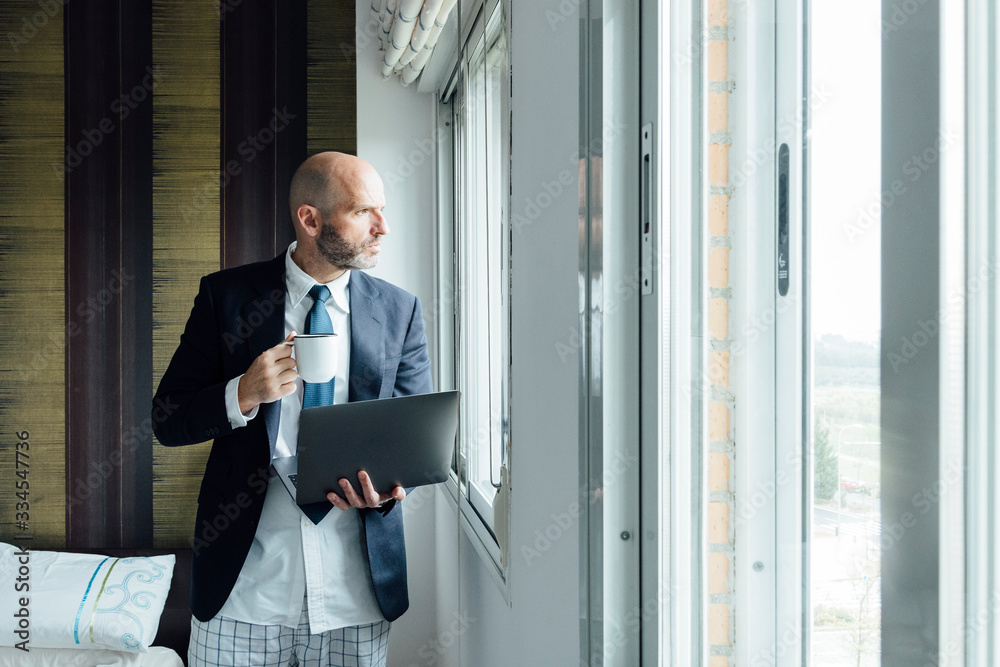 Fototapeta premium Businessman by the window with laptop and coffee