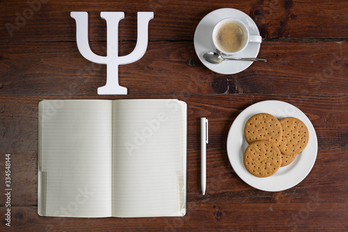 Symbol of psychology. Notebook, coffee cup and cookies on a wooden base. View from top. selective focus.