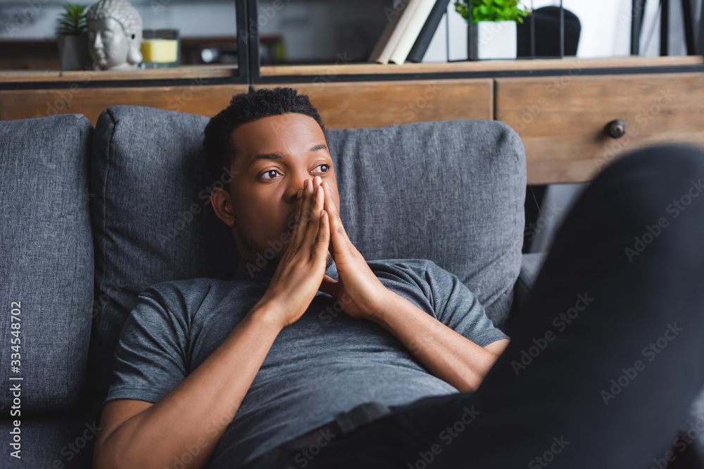 sad thoughtful african american man lying on sofa at home sad thoughtful african american man lying on sofa at home