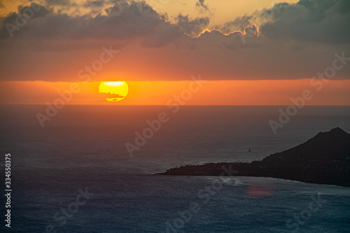 Fototapeta Naklejka Na Ścianę i Meble -  A sunset over the Hawaiian Island of Oahu as seen from a mountain top with Head in the distance.