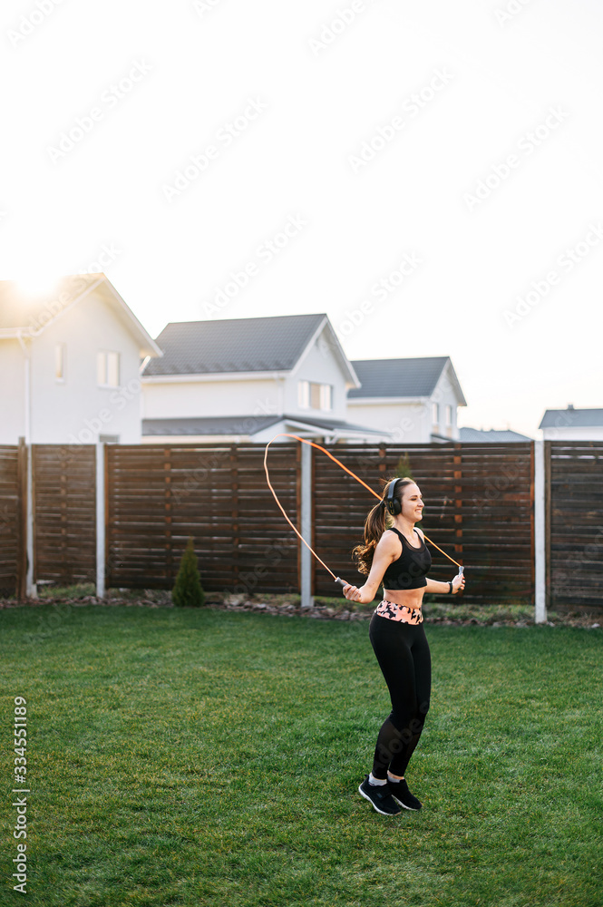 Fototapeta premium Young woman jumps with a skipping rope outdoors