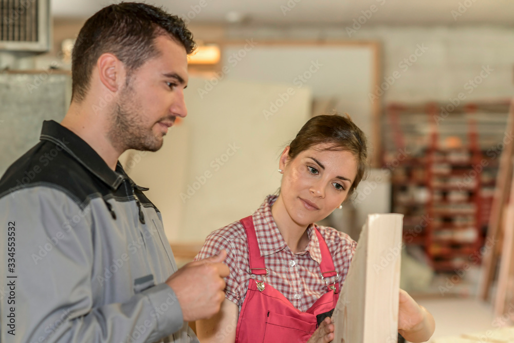 Female and male wood worker checking paperwork in workshop