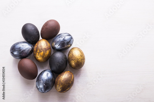 Holidays, traditions and Easter concept - Dark stylish easter eggs on white wooden background with copyspace.