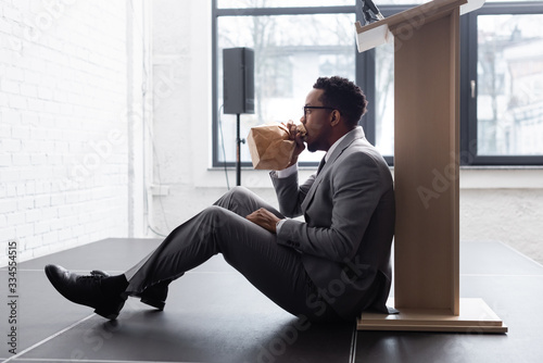 nervous african american speaker breathing with paper bag and having panic attack during business conference in office photo