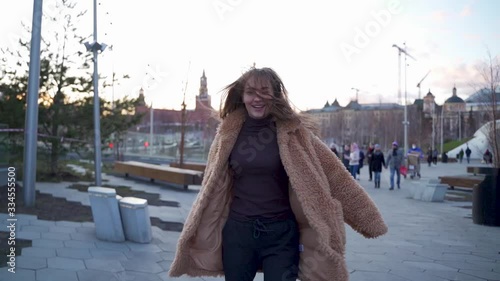 APRIL, 2020, MOSCOW, ZARYADYE PARK: following a lady, who is strolling and cheerfully spinning in the spring park on sunset