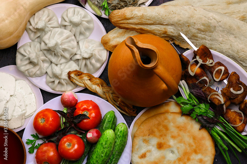 Traditional Georgian cuisine. Georgian dishes and wine jug. Top view of Georgian cuisine food set from khachapuri, kinkily, shot, roasted meat, fresh vegetables and wine. photo