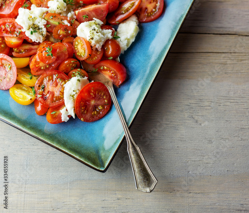 Close up of caprese salad with sliced cherry tomatoes and buffalo mozzarella. 