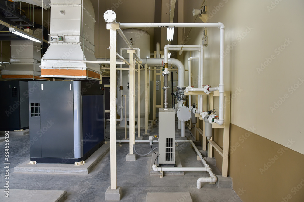 Obraz premium Compressor air machine with equipment piping air compressor system in the building utility room.