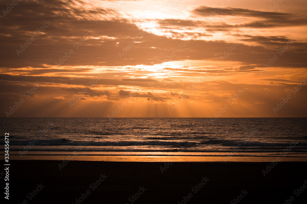 Dramatic Sunset Scene with Rays of Sun Light and Clouds over the Sea