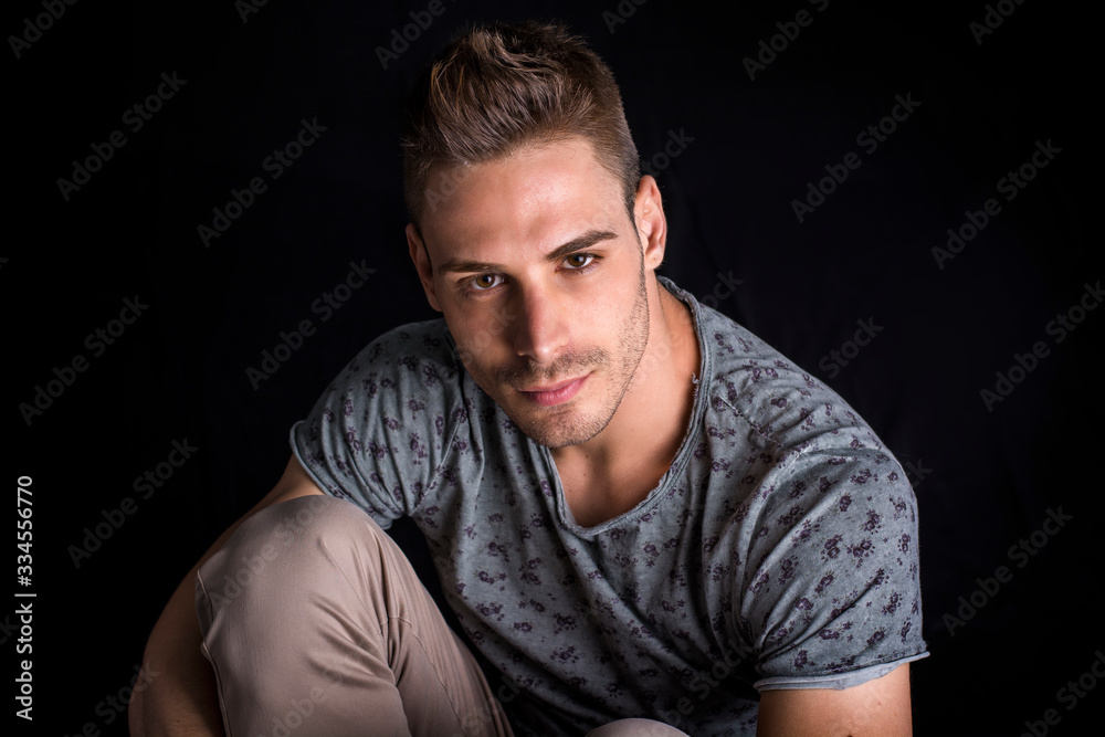 Attractive man with shirt, on dark background in studio, shot from above, looking at camera