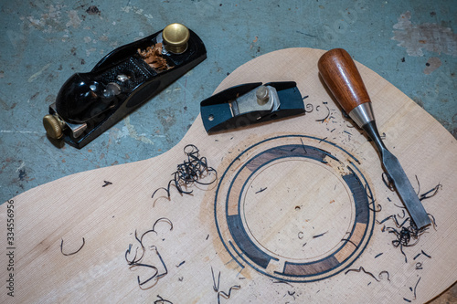 Luthier workbench with tools and a top of an acoustic guitar under construction photo