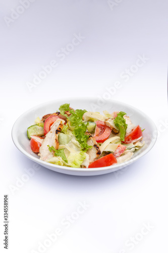 white deep plates with fresh salad ingredients mixed with sauce placed on isolated white background. A place for a menu, banner or advertisement