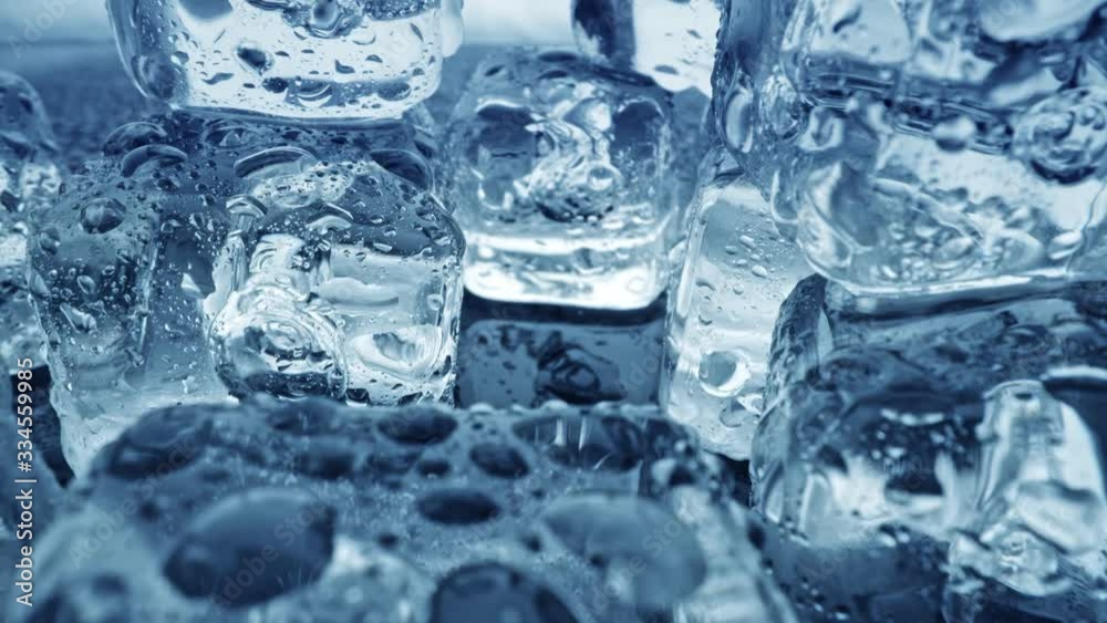 Melted ice cubes close up. Camera moves through ice cubes with water drops over dark background. UHD, 4K Melted ice cubes close up. Camera moves through ice cubes with water drops over dark background. UHD, 4K