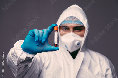 Coronavirus pandemia. Healthcare to aid recovery from COVID-19. Man wear surgical gloves and mask, biohazard protection clothing with a coronavirus infected blood sample test.