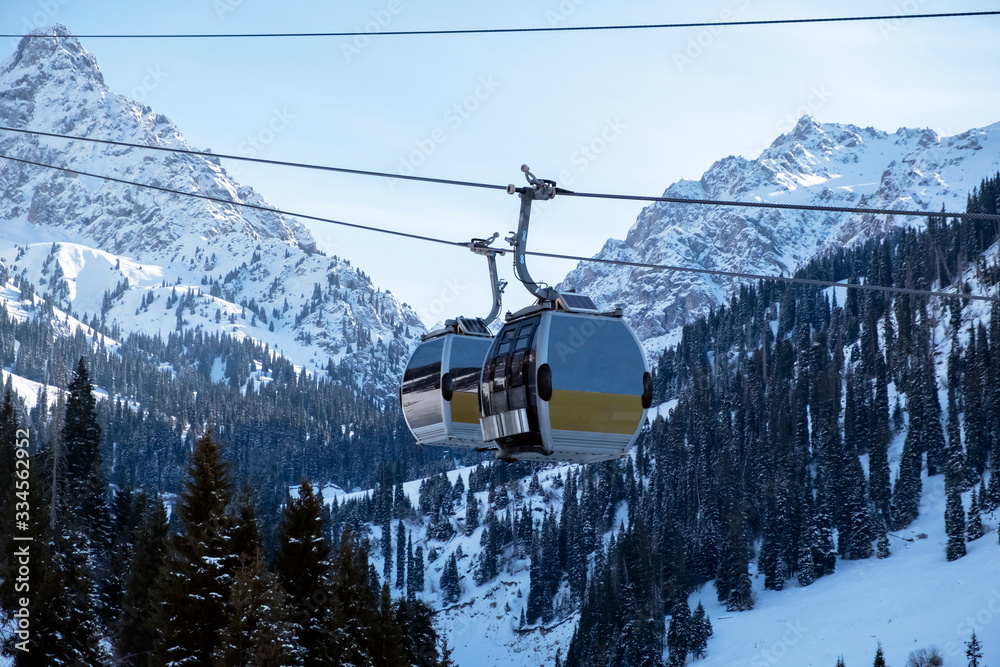 Cable car way on snowy mountains background. Gondola lift in winter mountains. Cable car way on snowy mountains background. Gondola lift in winter mountains.
