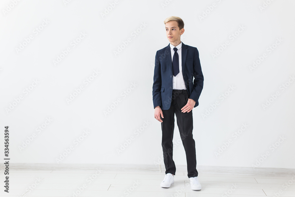 Portrait of stylish school boy teenager in white shirt and jacket against white background with copy space.