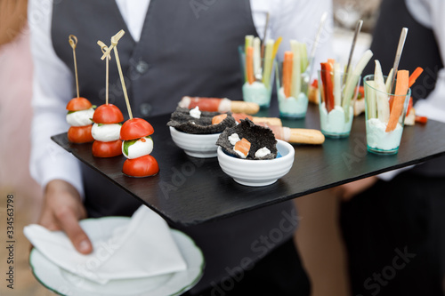 Small snacks lying on a tray. The waiter holds a tray of mouth-watering snacks