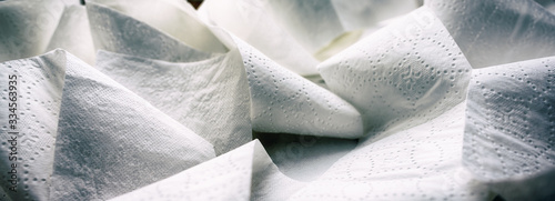 Close-up at folded unrolled white toilet paper. Banner proportioned high resolution image.