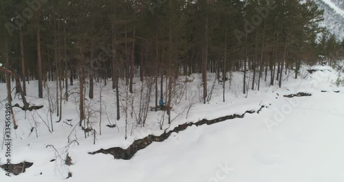 Snowmobile rides through a snowy forest along the river. The mountains