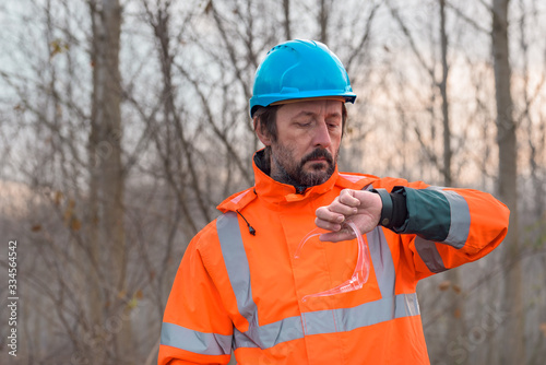 Forestry technician checking up on his smart watch