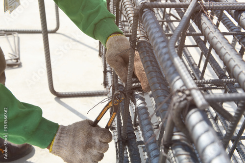 Worker using steel wire and pincers to secure main rebar for reinforcement in the construction work