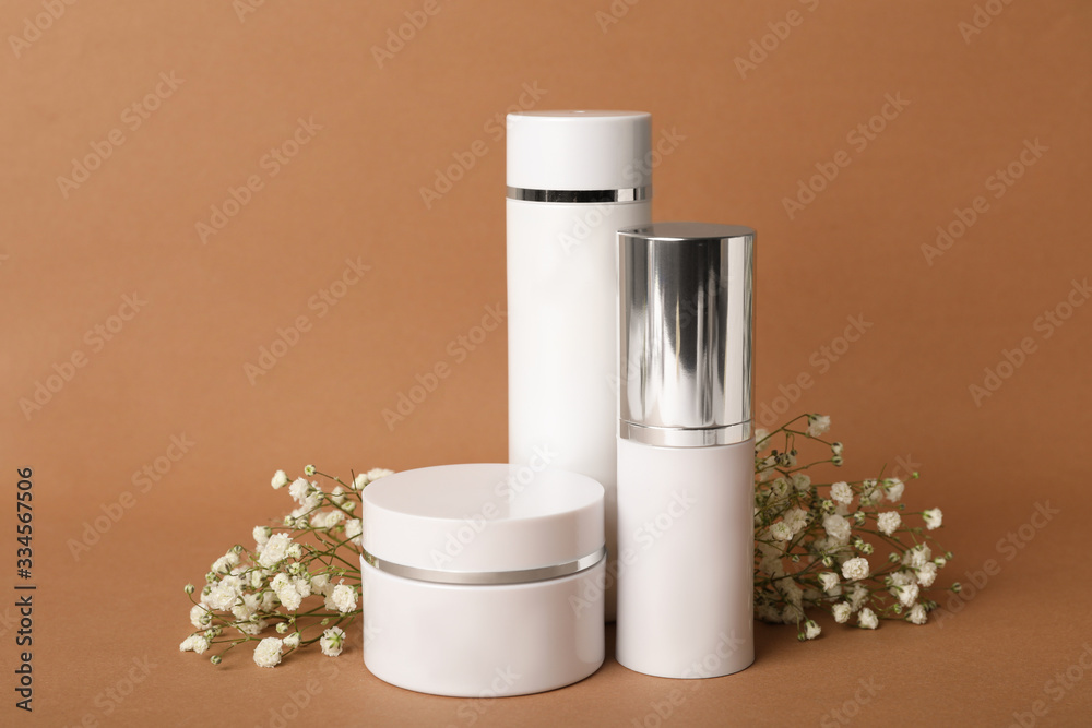 Set of luxury cosmetic products and flowers on brown background Set of luxury cosmetic products and flowers on brown background