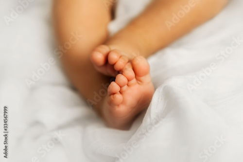 Newborn baby legs on white blanket, closeup of infant toes