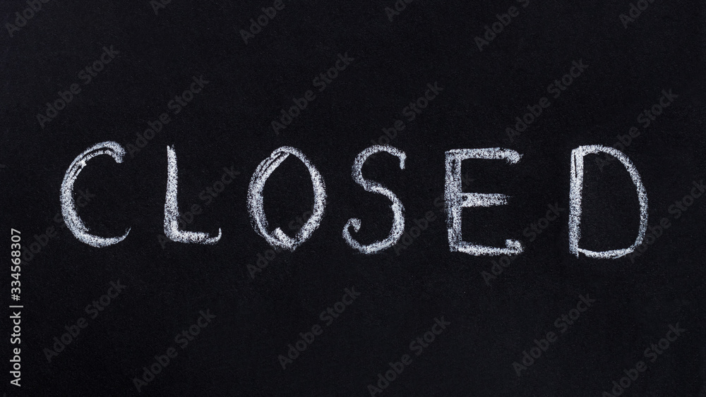 Fototapeta premium Drawing with chalk on a black blackboard with text closed