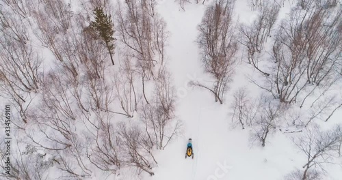 Snowmobile rides in a snowy forest. The mountains. Shot on a drone