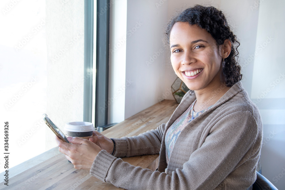 black business woman smiles at camera while texting on her phone black business woman smiles at camera while texting on her phone