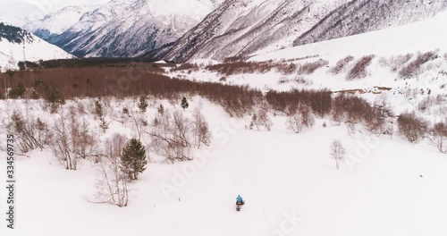 Snowmobile rides in a snowy forest. The mountains. Shot on a drone