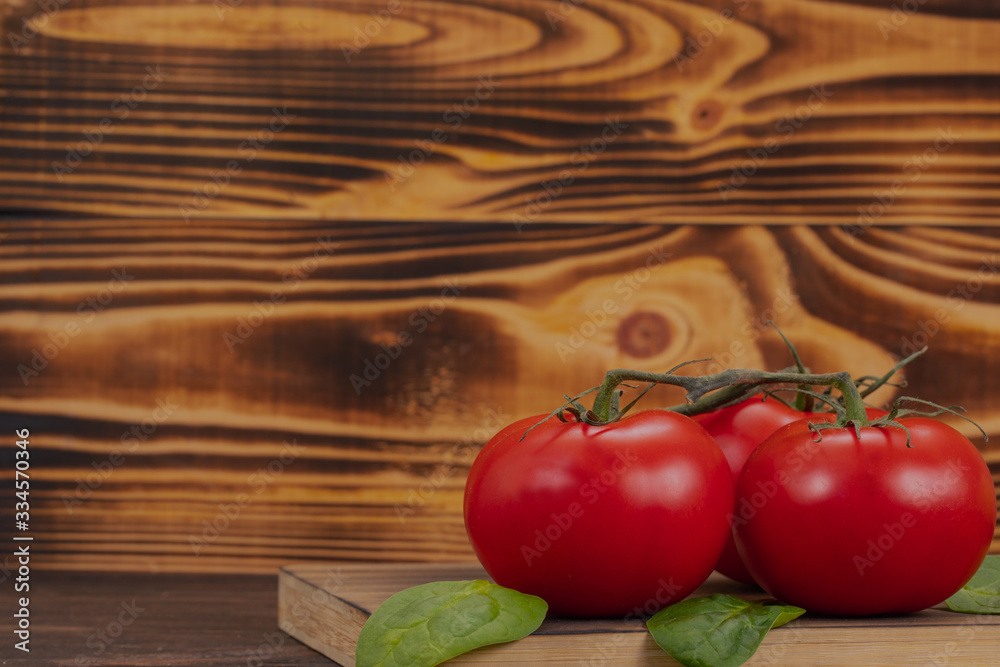 Delicious tomatoes on a cutting board with basil leaves on wooden background with space for text. Fresh vegetables for healthy eating Delicious tomatoes on a cutting board with basil leaves on wooden background with space for text. Fresh vegetables for healthy eating