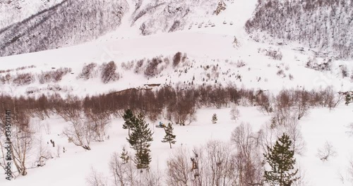 Snowmobile rides in a snowy forest. The mountains. Shot on a drone