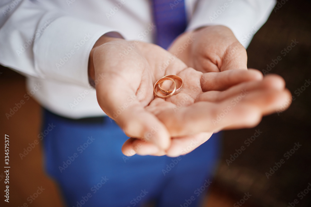 groom holds wedding rings in his hands