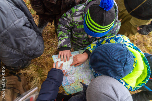 Children study maps of the area. Learning to navigate on the map while Hiking in the forest.