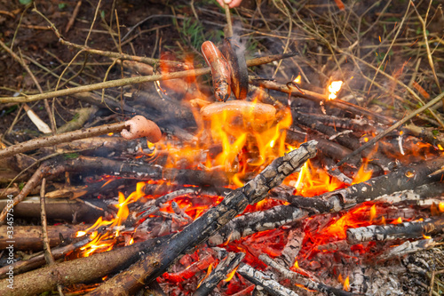 Fry sausages and bread on a campfire.