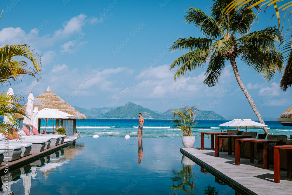 Φωτογραφία young men in swimming pool during sunset, Luxury swimming pool in tropical resort, relaxing holidays in Seychelles islands
