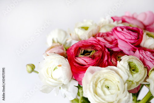 Macro shot of beautiful bouquet of pink   white ranunculus flowers with visible petal texture . Close up composition with bright patterns of flower buds with a lot of copy space for text. Top view.