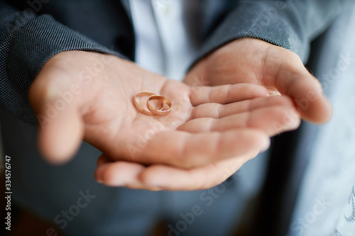 groom holds wedding rings in his hands